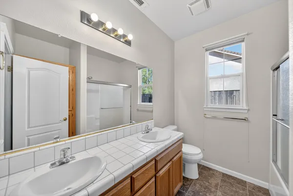 a bathroom with a granite countertop sink a toilet and a mirror