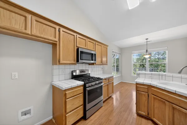 a kitchen with stainless steel appliances granite countertop a stove a sink and a microwave