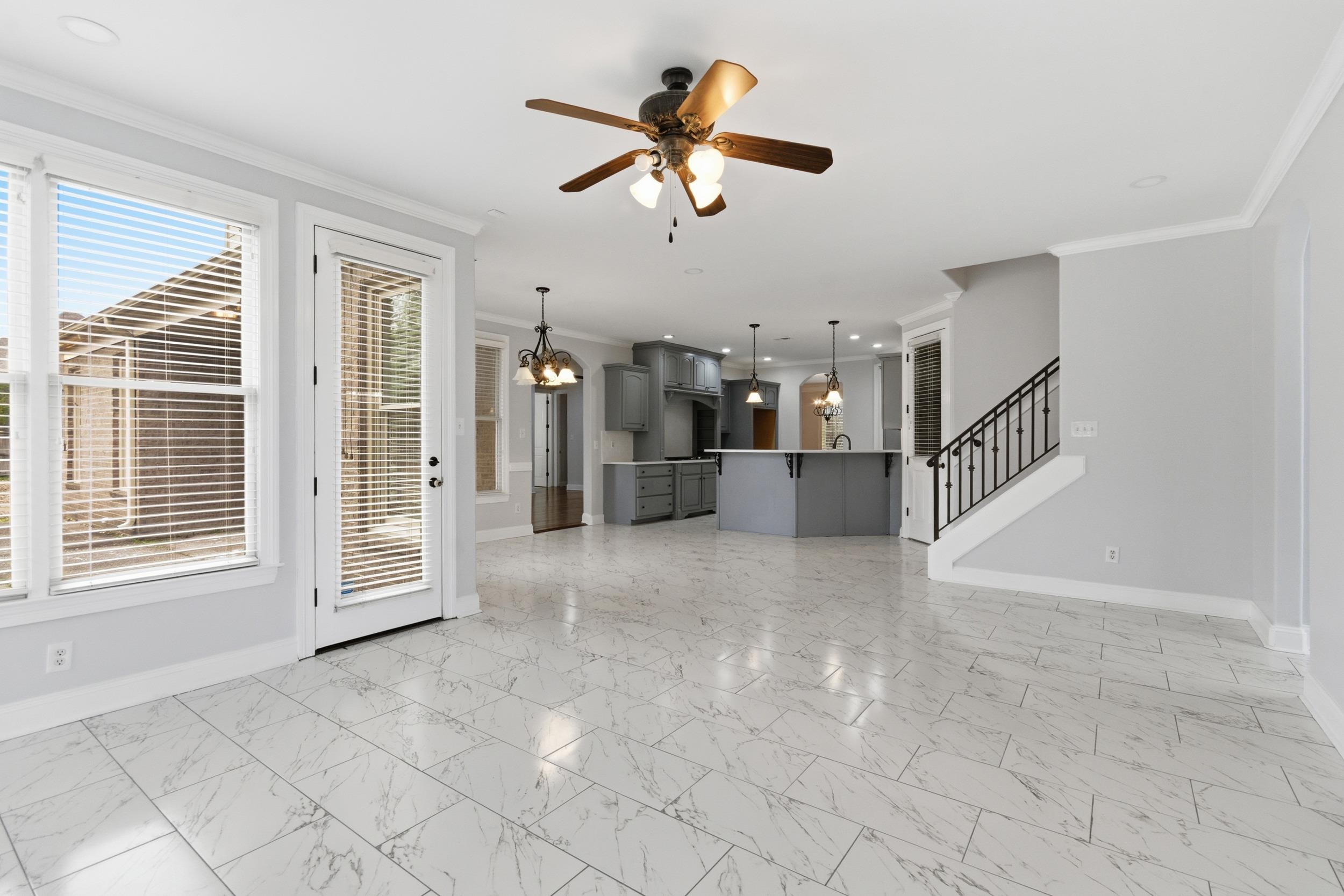 11080 Shelby Post Road Collierville, TN 38017 - Photo 8 of 39 Unfurnished living room with a chandelier, crown molding, light marble finish flooring, stairway, and a ceiling fan
