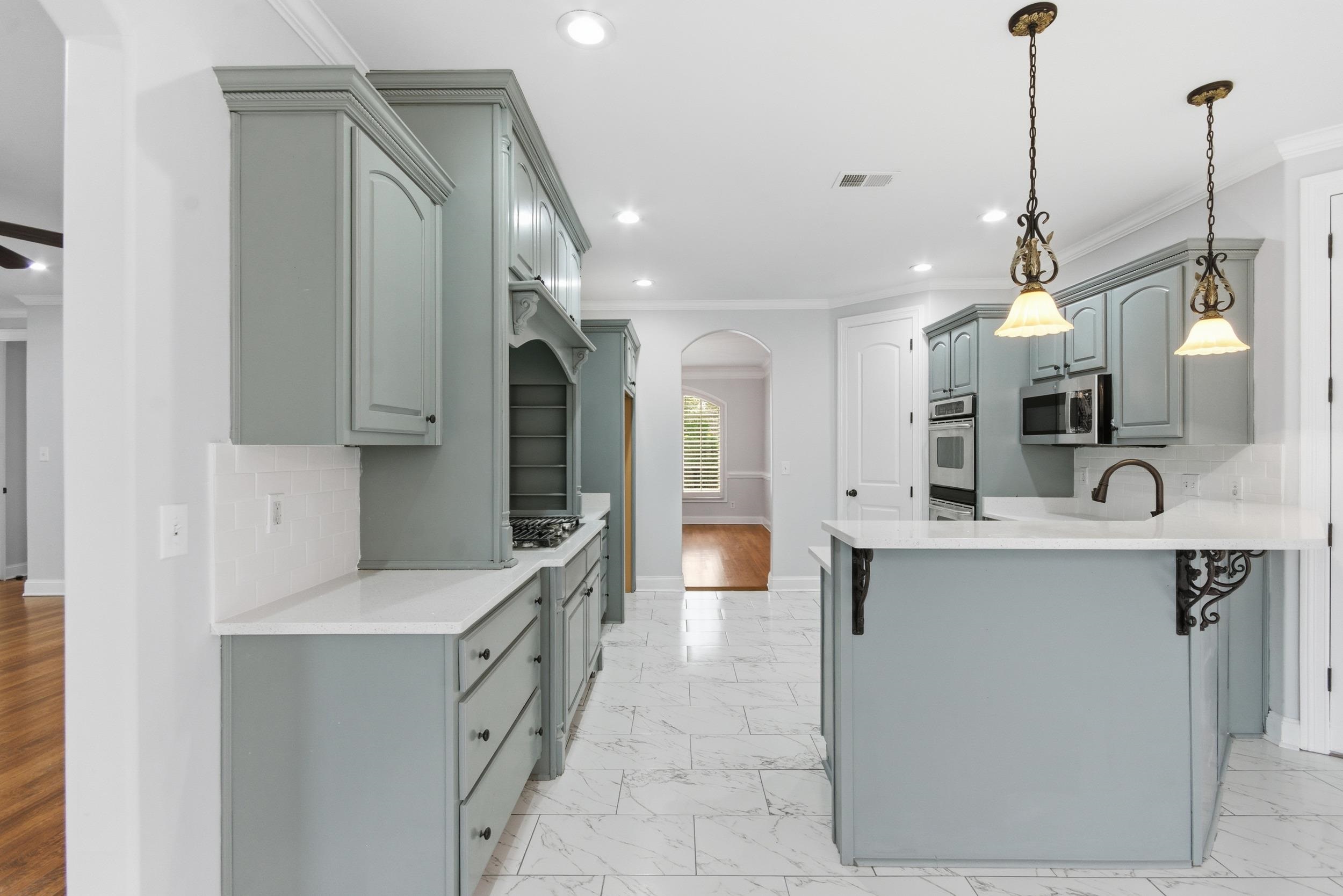 11080 Shelby Post Road Collierville, TN 38017 - Photo 9 of 39 Kitchen with backsplash, arched walkways, light marble finish flooring, ornamental molding, and gray cabinets