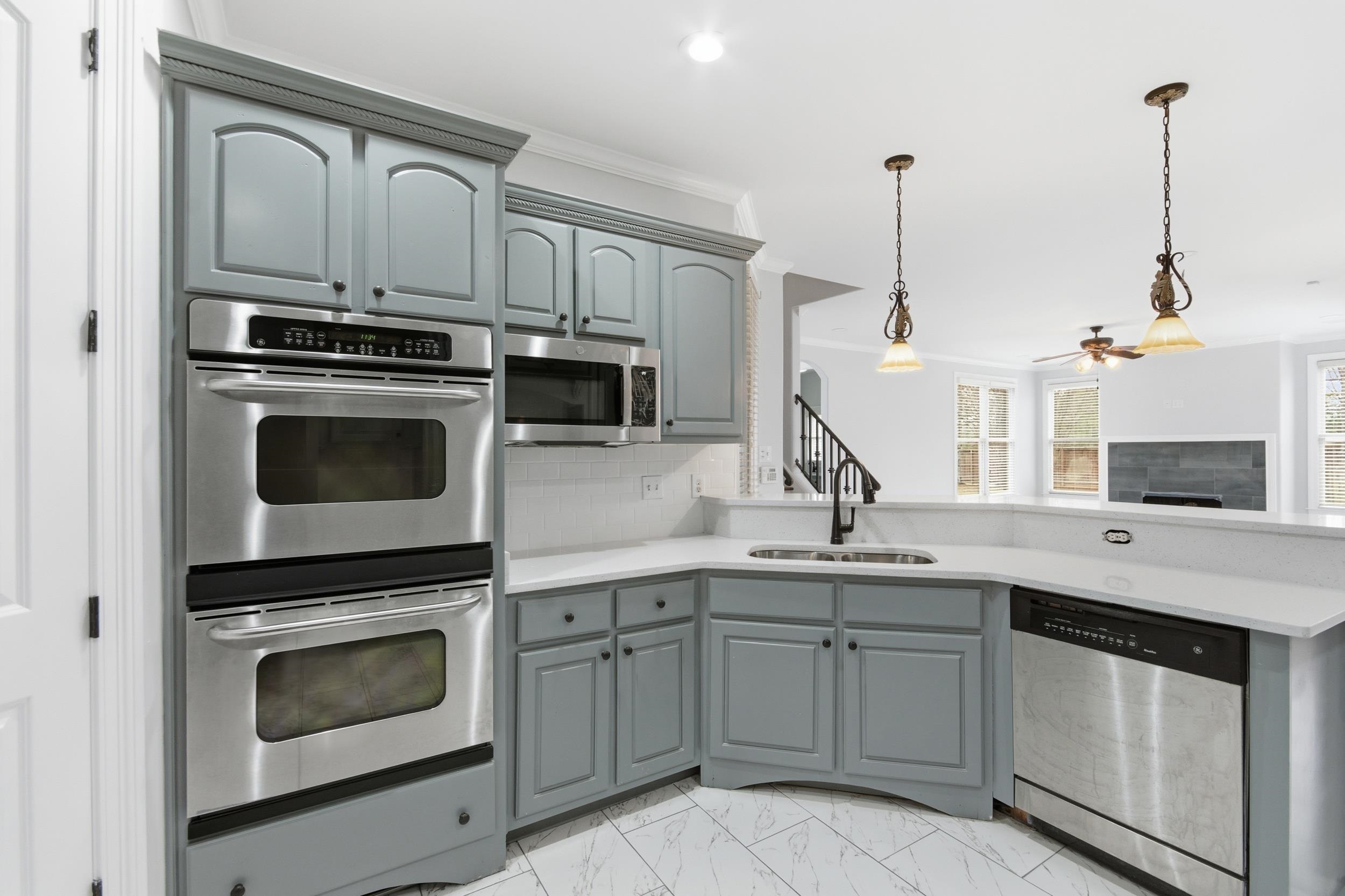 11080 Shelby Post Road Collierville, TN 38017 - Photo 10 of 39 Kitchen featuring appliances with stainless steel finishes, gray cabinetry, backsplash, decorative light fixtures, and light marble finish floors