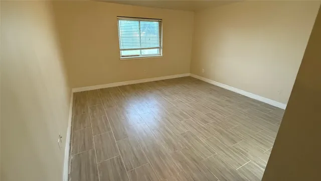 an empty room with wooden floor and fan