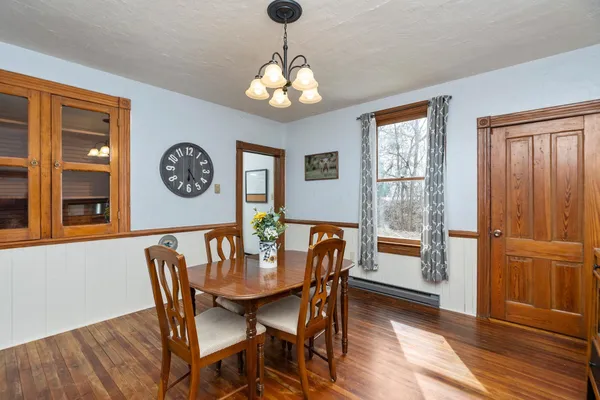 a dining room with wooden floor a chandelier a wooden table and chairs