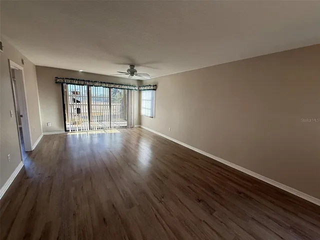 a view of an empty room with wooden floor and a window