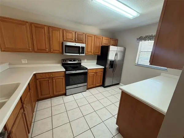 a kitchen with stainless steel appliances a stove a microwave a sink a refrigerator white cabinets and black appliances