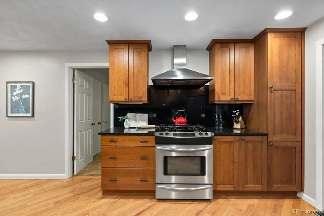 a kitchen with stainless steel appliances kitchen island granite countertop a refrigerator a stove a sink dishwasher and white cabinets with wooden floor
