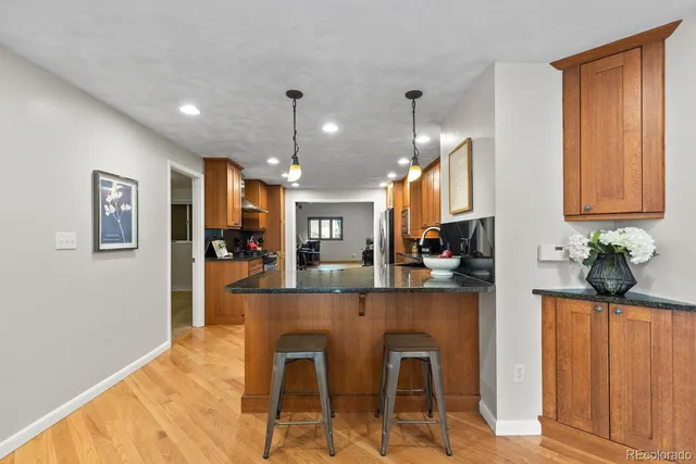 a kitchen with stainless steel appliances kitchen island granite countertop wooden cabinets a dining table and chairs