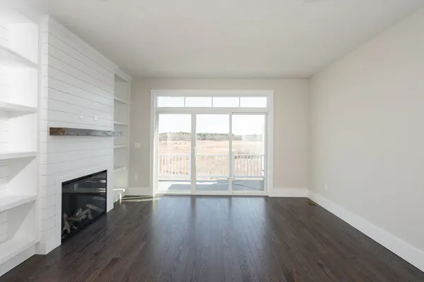 an empty room with wooden floor fireplace and windows