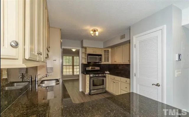 a kitchen with stainless steel appliances granite countertop a stove a sink and a refrigerator