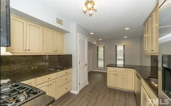 a kitchen with stainless steel appliances kitchen island granite countertop a stove a sink and white cabinets