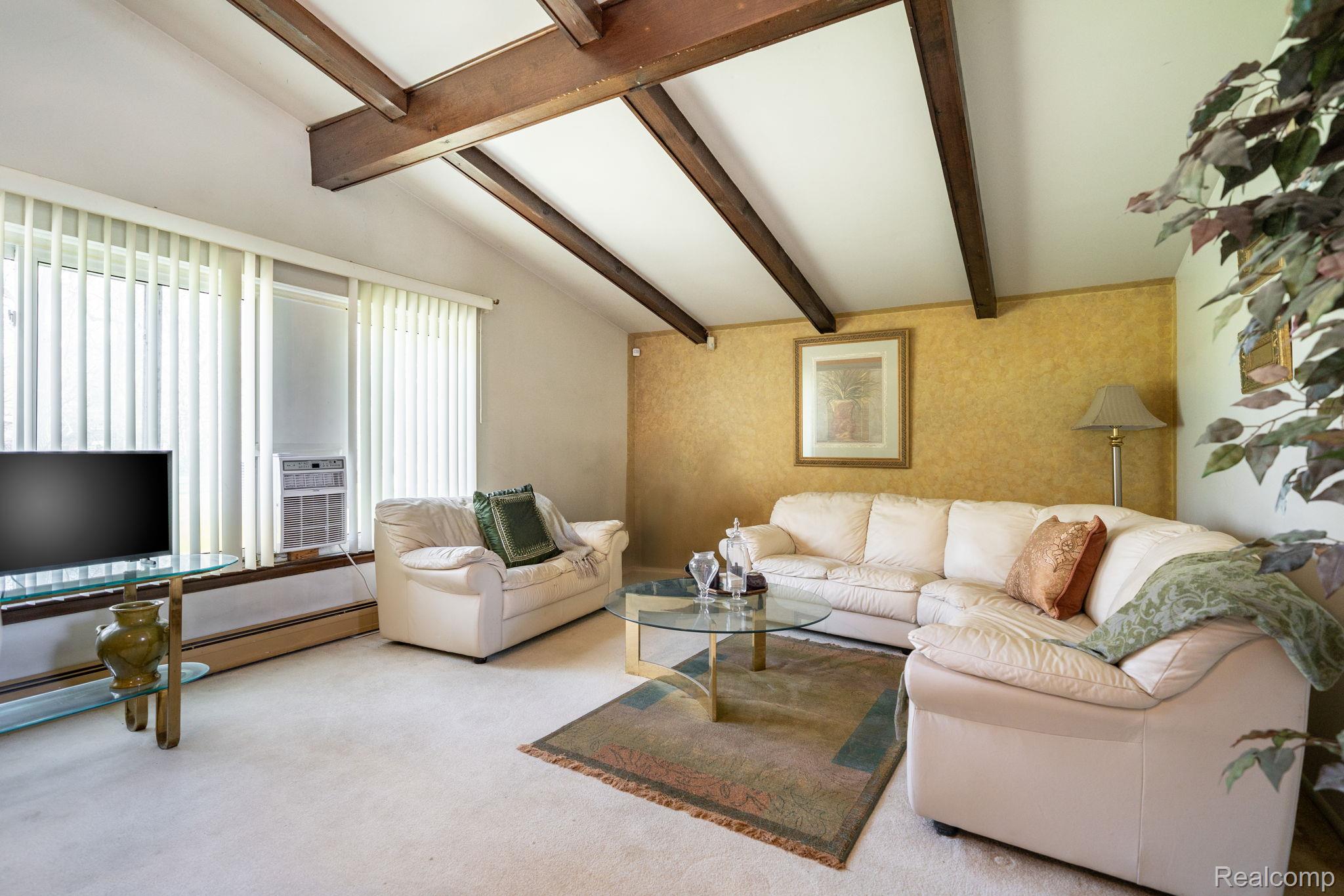 Living room featuring carpet and vaulted ceiling with beams