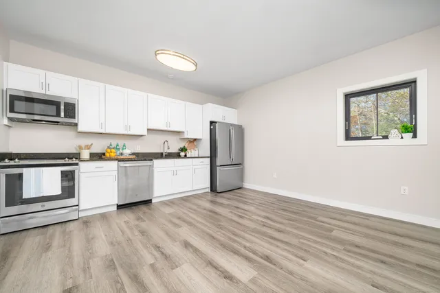 a kitchen with stainless steel appliances white cabinets and wooden floor