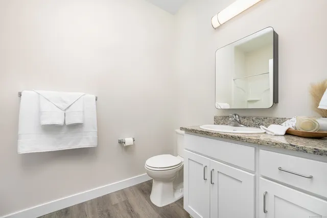 a bathroom with a granite countertop sink and a toilet