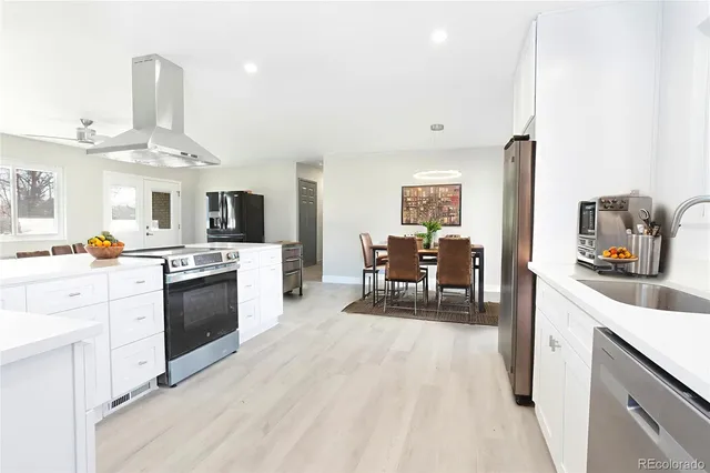 a kitchen with stainless steel appliances a stove top oven a sink a dining table and chairs