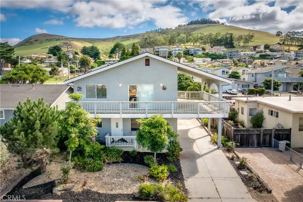 a view of a white house next to a yard with potted plants