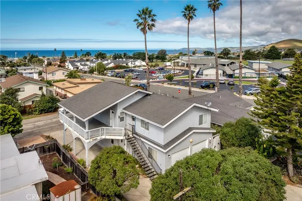 a view of a white house with a yard and lawn chairs under an umbrella