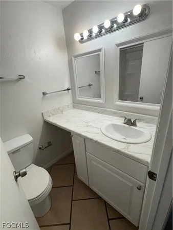 a bathroom with a granite countertop sink toilet a mirror and vanity