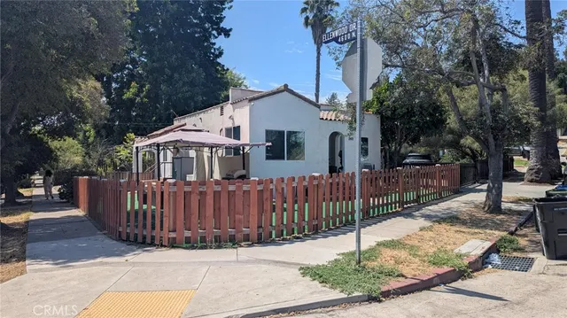 a view of a white house with a small yard and wooden fence