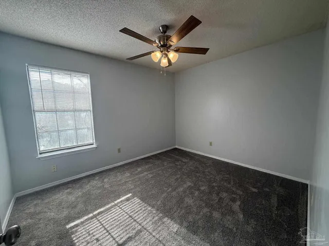 an empty room with window and ceiling fan