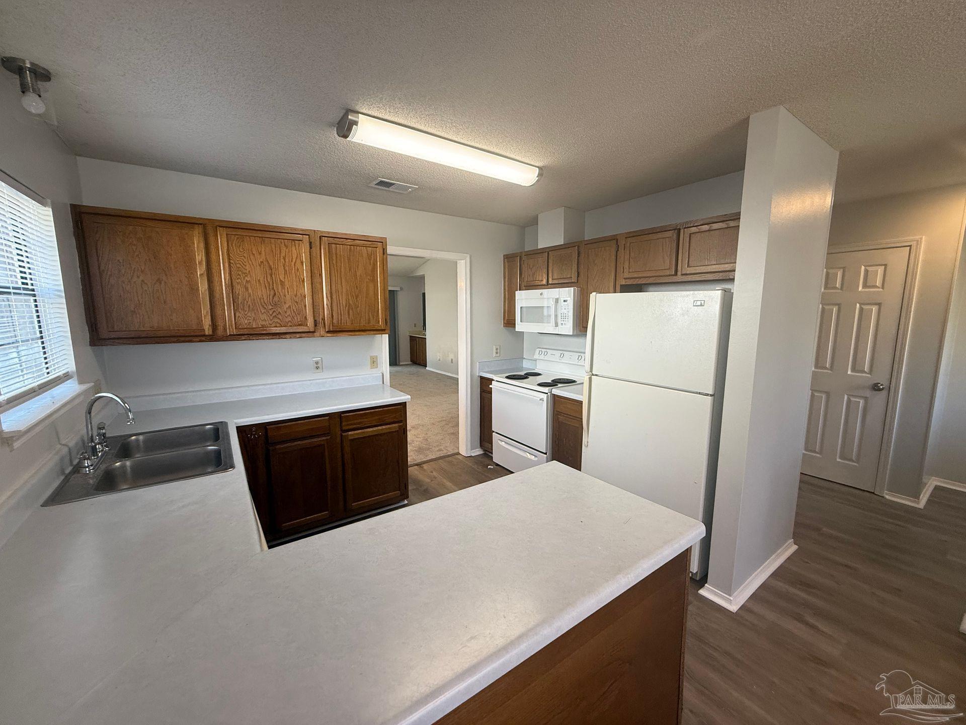 2715 Summertree Lane Gulf Breeze, FL 32563 - Photo 7 of 25 a kitchen with sink a refrigerator and wooden cabinets