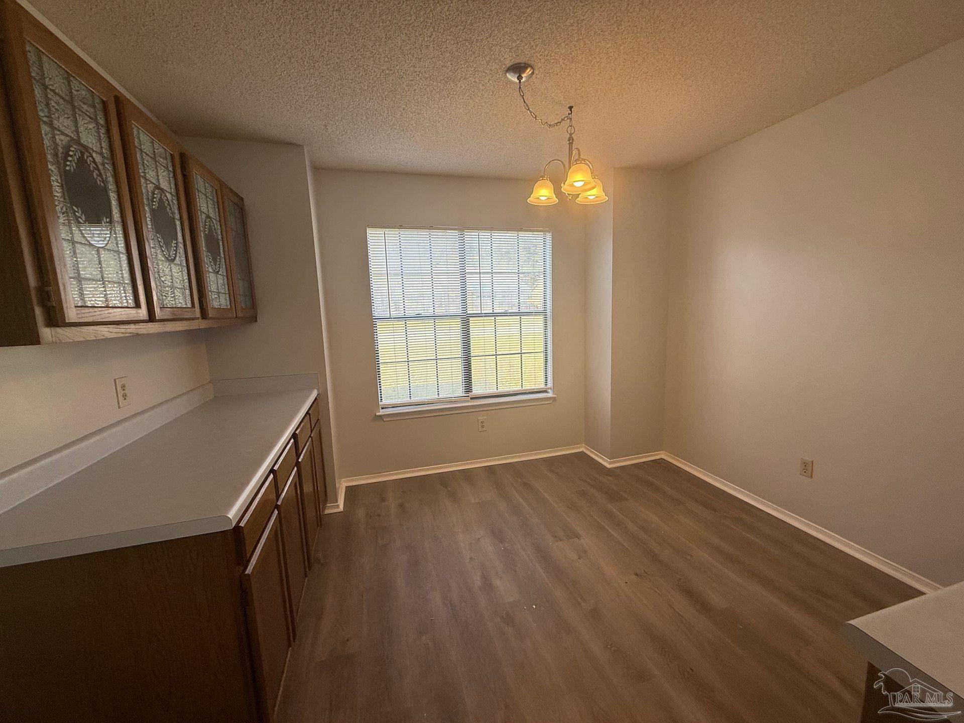 2715 Summertree Lane Gulf Breeze, FL 32563 - Photo 8 of 25 an empty room with wooden floor chandelier and windows
