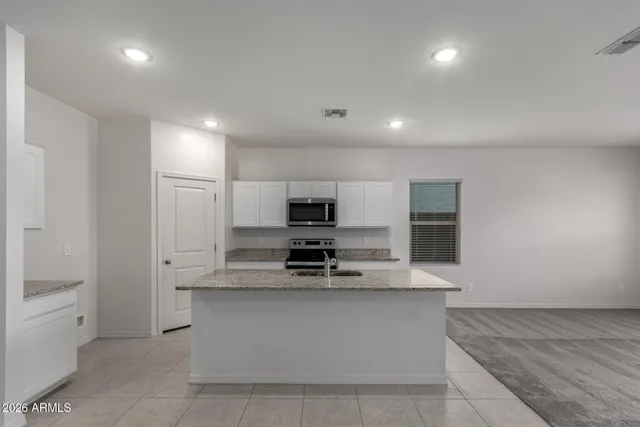 a large kitchen with stainless steel appliances a large counter top a stove and a refrigerator