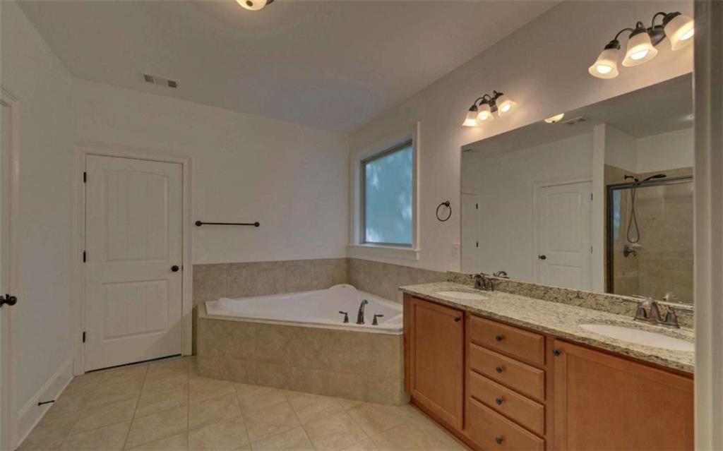 255 Abbington Way Clarkesville, GA 30523 - Photo 24 of 49 a bathroom with a sink double vanity granite tub and a mirror