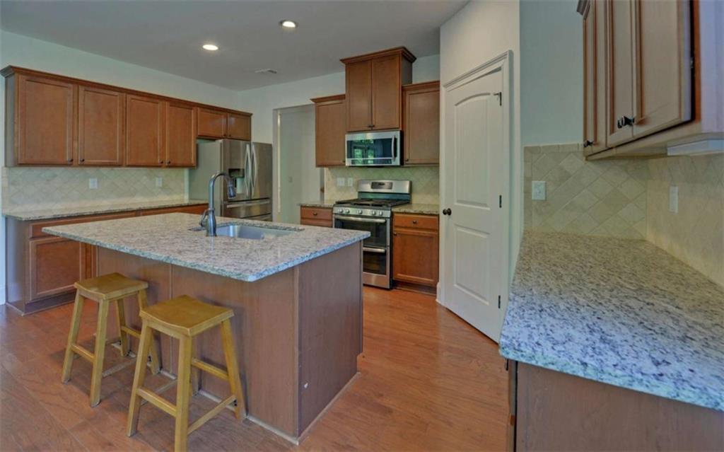 255 Abbington Way Clarkesville, GA 30523 - Photo 10 of 49 a kitchen with kitchen island granite countertop wooden cabinets and a refrigerator