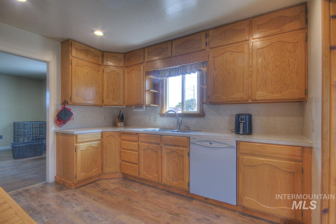 351 West Main Street South Vale, OR 97918 - Photo 5 of 33 Kitchen featuring natural wood cabinetry, light-toned countertops, a stainless steel sink with a gooseneck faucet, a built-in dishwasher, and wood-finish flooring