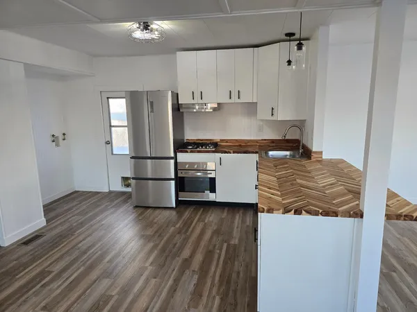 a kitchen with stainless steel appliances granite countertop a refrigerator a stove and a wooden floors