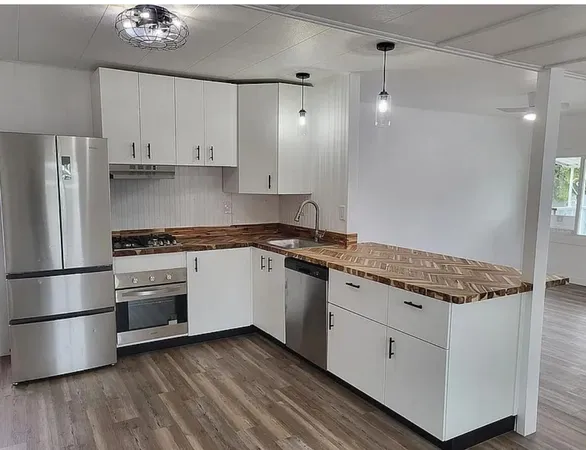 a kitchen with stainless steel appliances granite countertop a refrigerator a sink dishwasher a stove and white cabinets