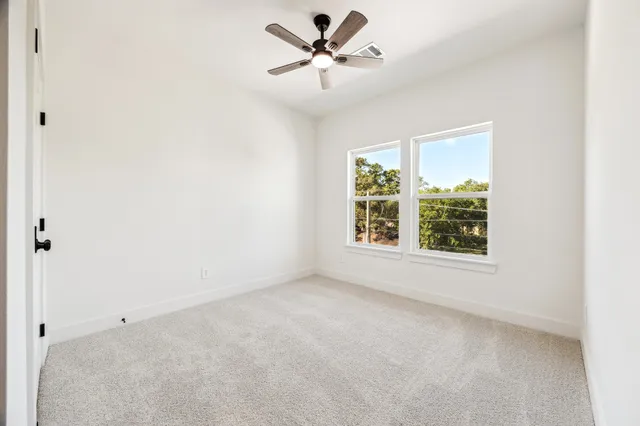 an empty room with a window and a ceiling fan