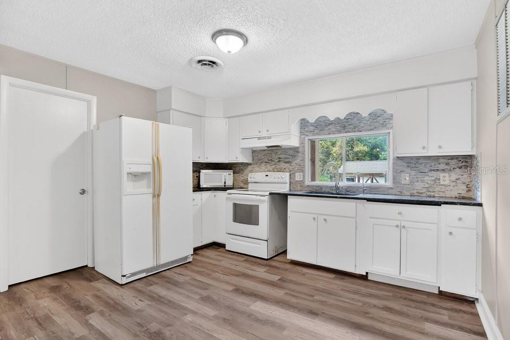 5137 Mt Plymouth Road Apopka, FL 32712 - Photo 48 of 58 a kitchen with granite countertop white cabinets and white appliances
