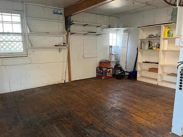 a view of empty room with wooden floor and window