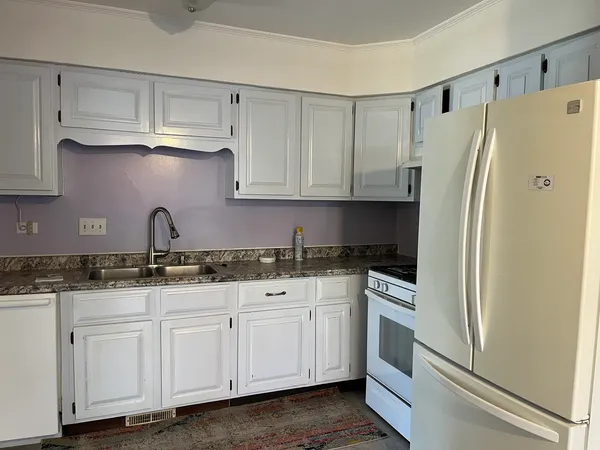 a kitchen with granite countertop white cabinets and refrigerator