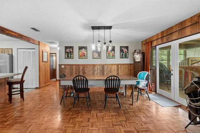 a dining room with furniture a chandelier and wooden floor