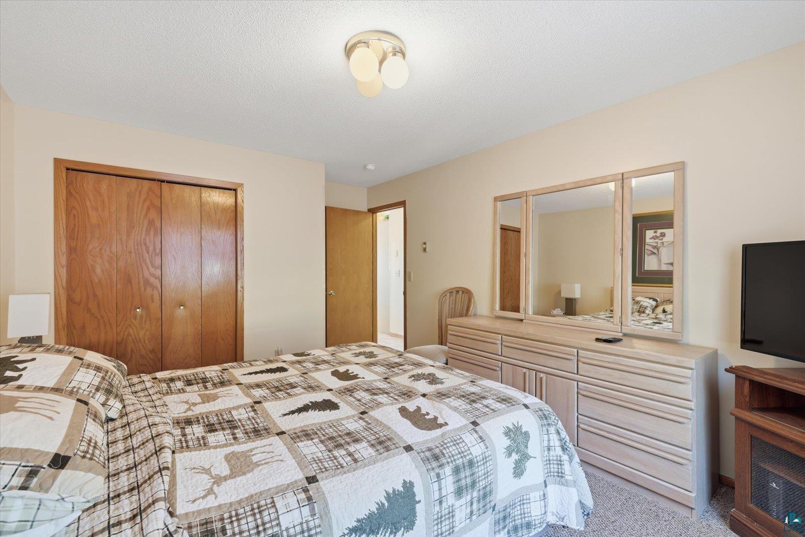 6266 Giants Ridge Road Biwabik, MN 55705 - Photo 26 of 29 Neutral-toned bedroom featuring wood-finish bi-fold closet doors, a ceiling-mounted light fixture, and carpet flooring
