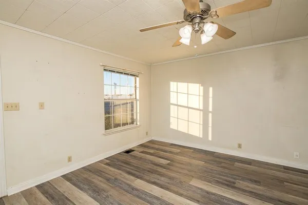 an empty room with wooden floor chandelier fan and windows