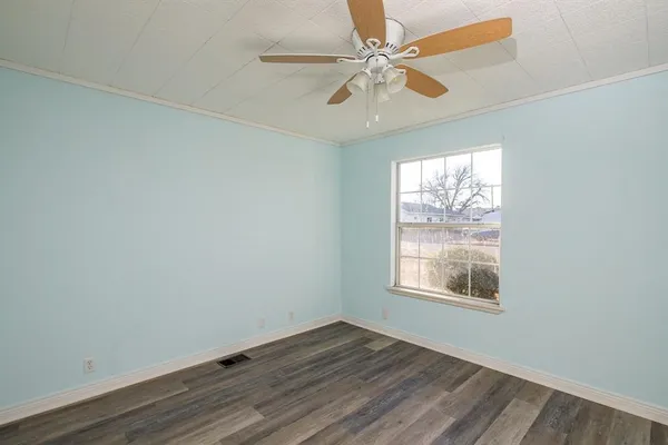 an empty room with wooden floor chandelier fan and windows