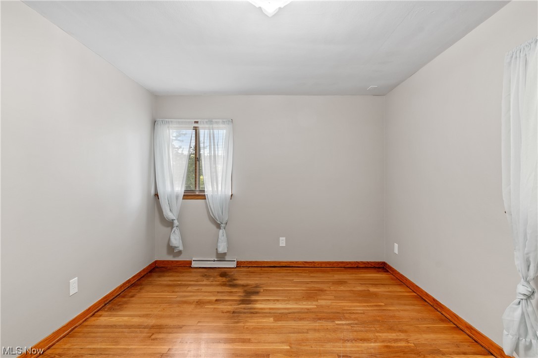 120 Lester Road New Franklin, OH 44319 - Photo 16 of 24 Hardwood floored empty room with a baseboard heating unit and a skylight