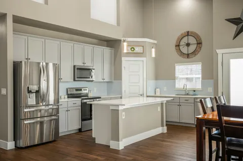 a kitchen with a sink cabinets stainless steel appliances and wooden floor