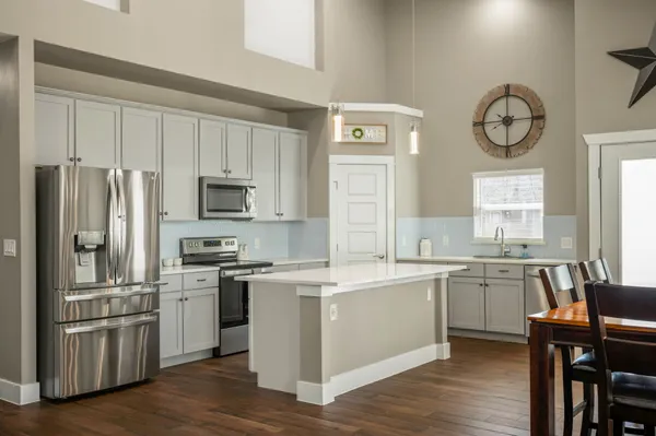 a kitchen with a sink cabinets stainless steel appliances and wooden floor