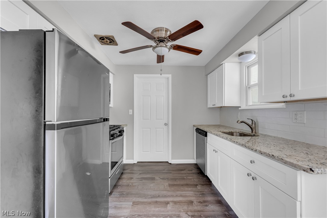 8043 Munson Road Mentor, OH 44060 - Photo 12 of 27 Kitchen featuring stainless steel appliances, white cabinets, hardwood / wood-style floors, backsplash, and ceiling fan