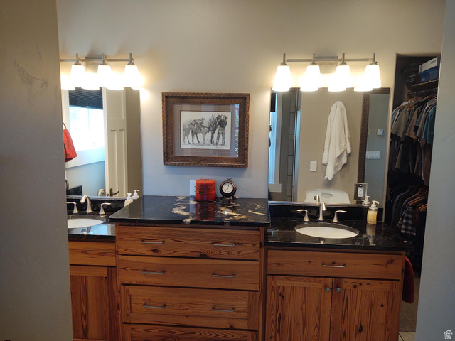 2170 Highway 357 Beaver, UT 84713 - Photo 27 of 56 Dual vanity with wood-finish cabinetry, black countertops, and undermount sinks