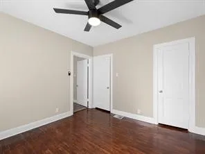 an empty room with wooden floor and ceiling fan