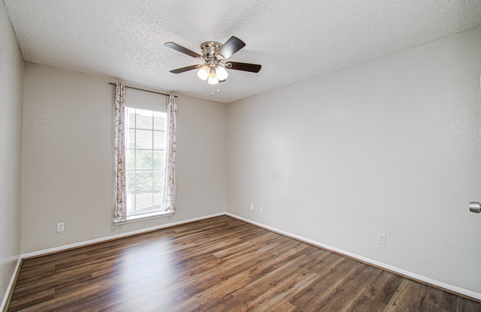 10101 South Gessner Road, Unit 405 Houston, TX 77071 - Photo 21 of 27 an empty room with wooden floor chandelier fan and windows