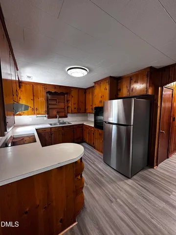 a kitchen with stainless steel appliances granite countertop a refrigerator a sink a stove and a wooden floors