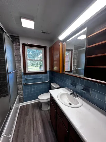a bathroom with a sink a toilet a mirror and window
