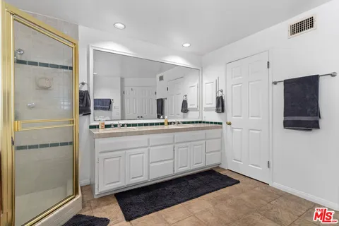 a spacious bathroom with a shower a sink and a mirror