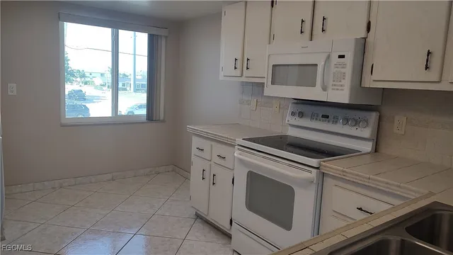 a kitchen with white cabinets and white appliances